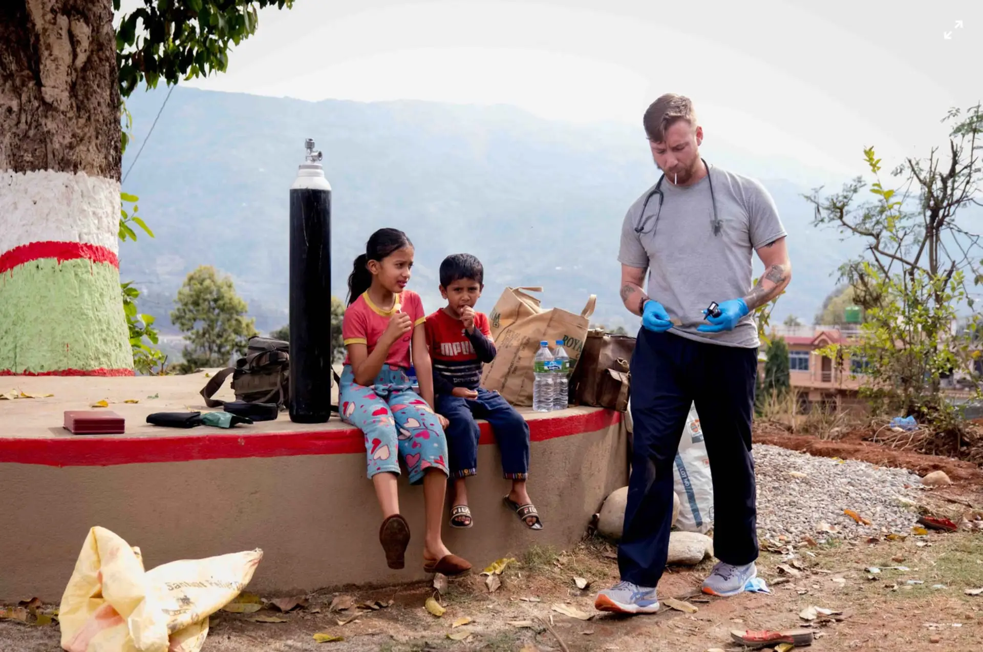 Doctor wearing blue gloves and wearing a stethoscope next to two children
