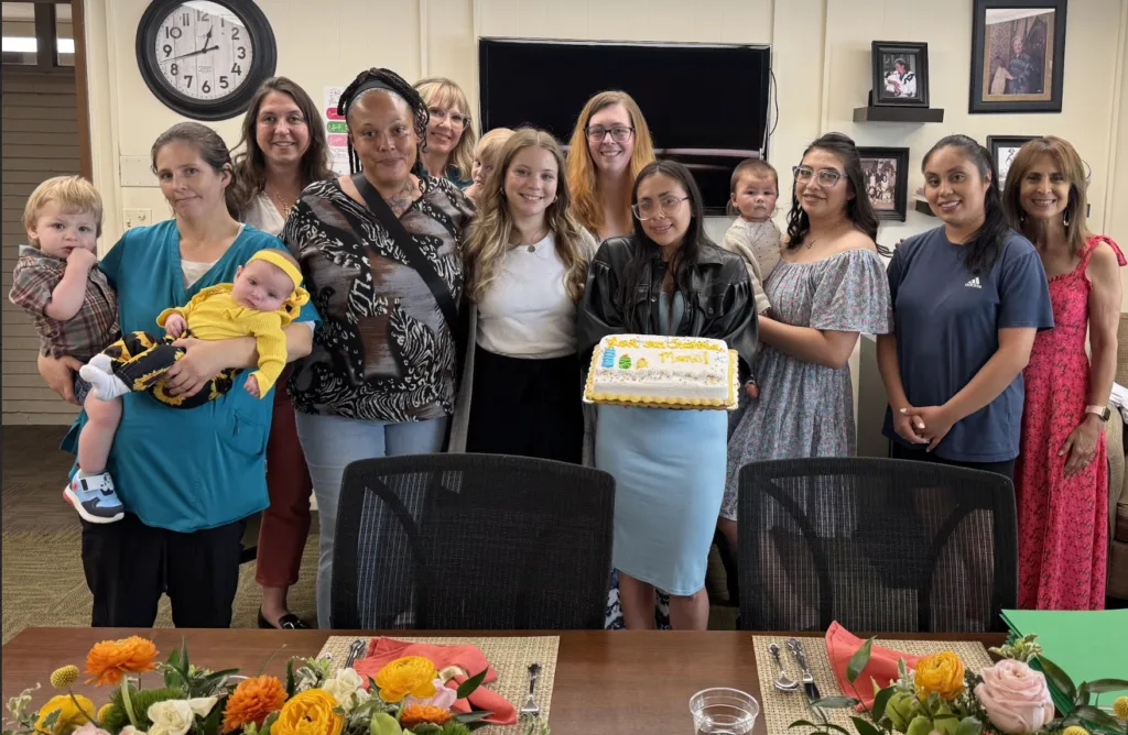 A large group of women and some children holding a cake
