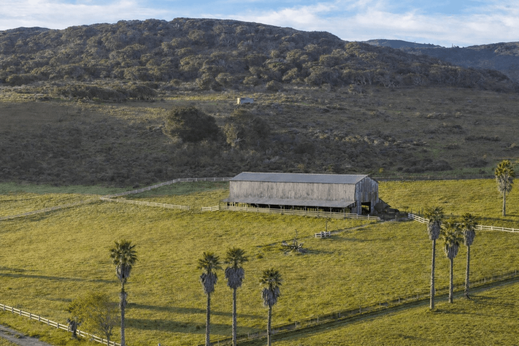 Barn in a grassy field with the words Hillside Ranch on it